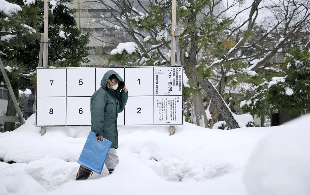 1月26日，日本福井縣，行人走過眾議院選舉海報公告板，地面堆滿積雪。（圖／路透社）