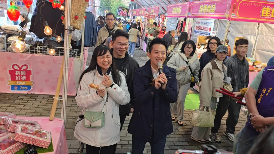 農曆新年將至，桃園藝文特區年貨採買人潮多，總統府副秘書長何志偉7日前往掃街，代表賴總統向民眾拜早年，不少攤商與市民要求合照，何志偉還幫忙推銷年貨，人氣超高。（圖／民眾提供）
