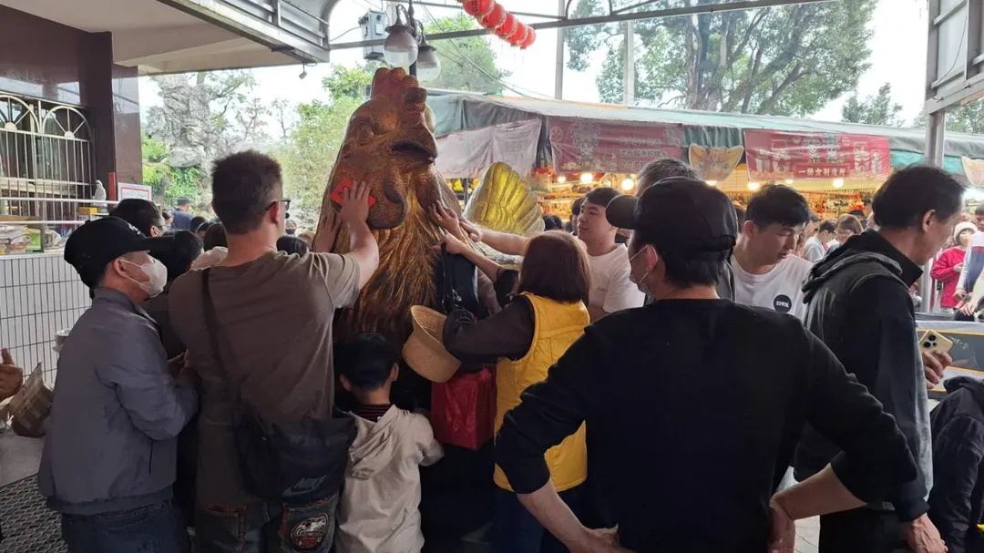 信眾們爭先恐後摸紫南宮廟前的大金雞,想要招來更多財運。(圖/中天新聞)