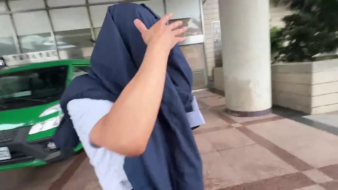 邱姓副院長一出法院在友人護駕下，用外套遮臉倉皇落跑。（圖／中天新聞）