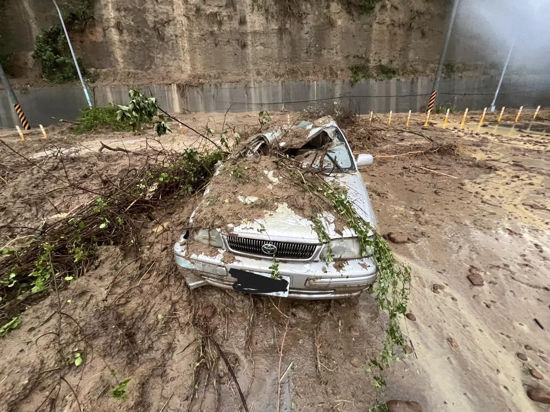 受苗栗大雨影響，竹南鎮苗9線往五福大橋路段發生邊坡坍方，大量土石崩落壓中一輛自小客車，車輛幾乎遭泥流淹沒。（圖／警方提供）