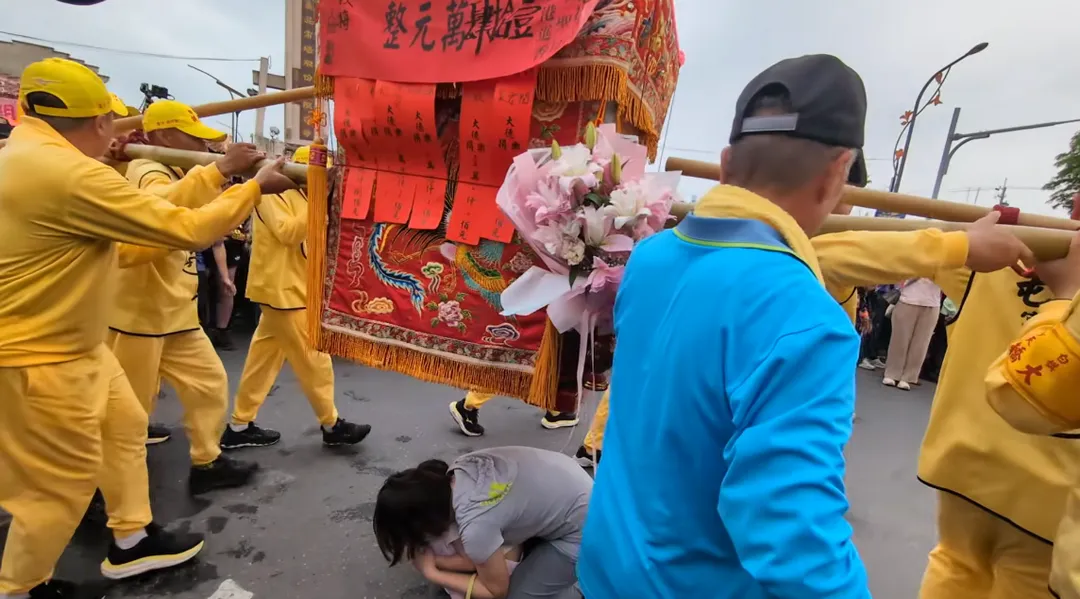 母女二人在指引下跪地鑽轎腳。（圖／翻攝自白沙屯媽祖網路電視台YouTube）
