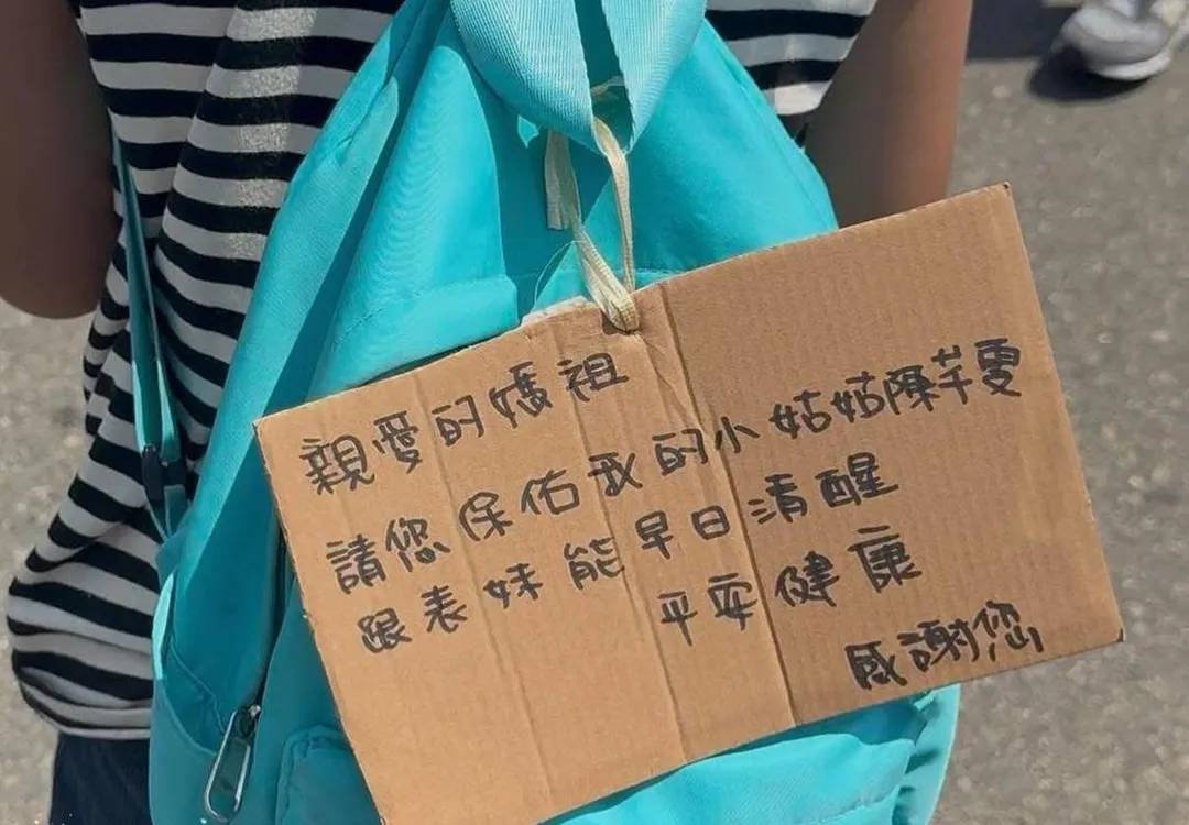 北市中正一分局女警陳芊雯產後血崩驟逝，疑似她的姪女在其搶救期間背上祈福紙板走上白沙屯媽祖進香隊伍祈禱。（圖／屁昂絲玩什麼授權提供）