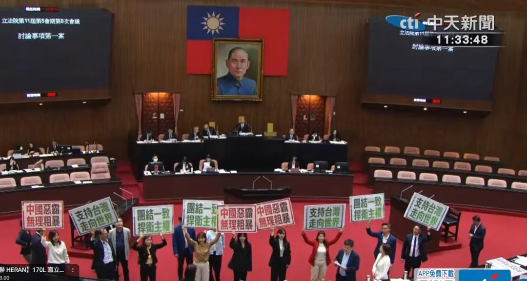 賴清德總統出訪受阻，立法院院會處理民進黨立委提出的譴責案，綠委在議場發言台前舉牌示威。（中天新聞）