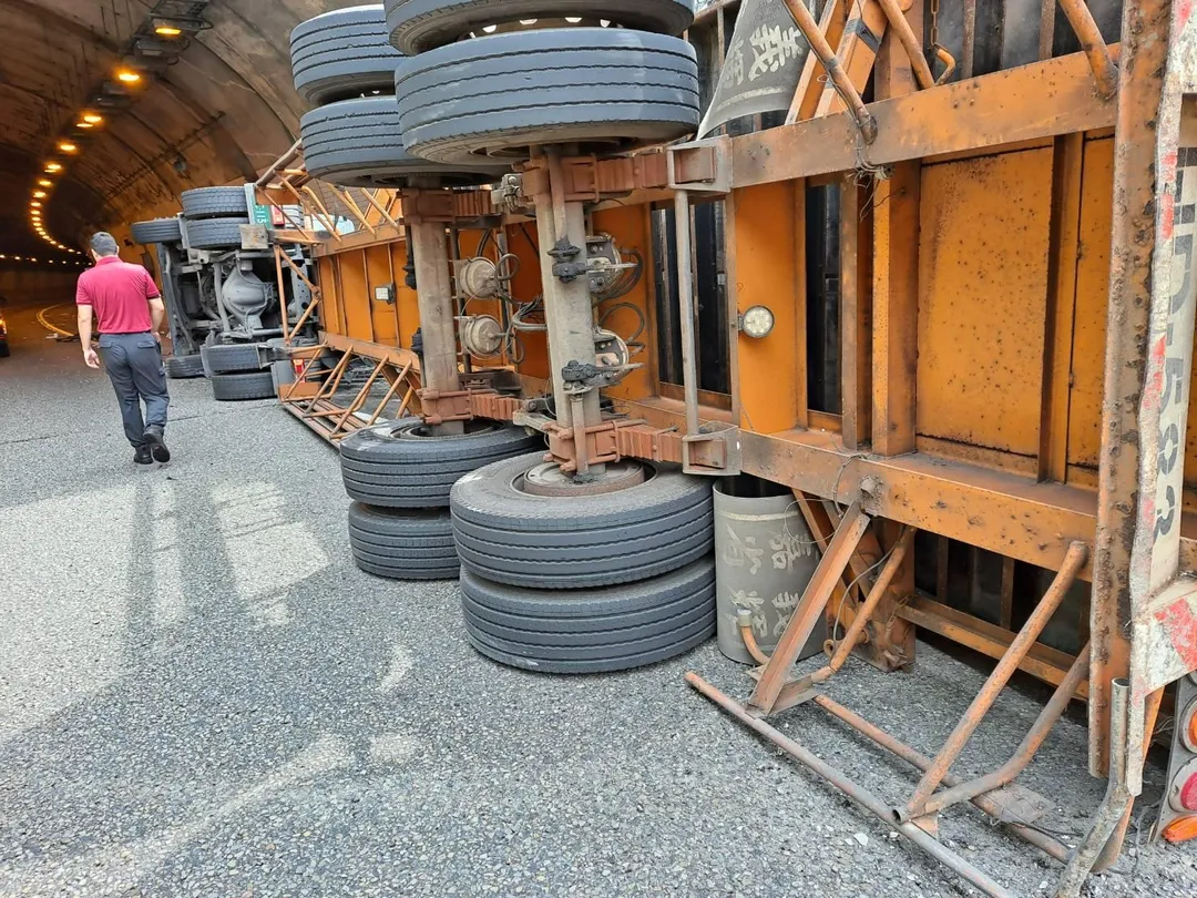 翻覆的聯結車車體側翻，車頂因撞擊而凹陷，佔用了隧道入口的大半個車道，導致南下車流一度受阻，僅能單線通行。（圖／翻攝畫面）
