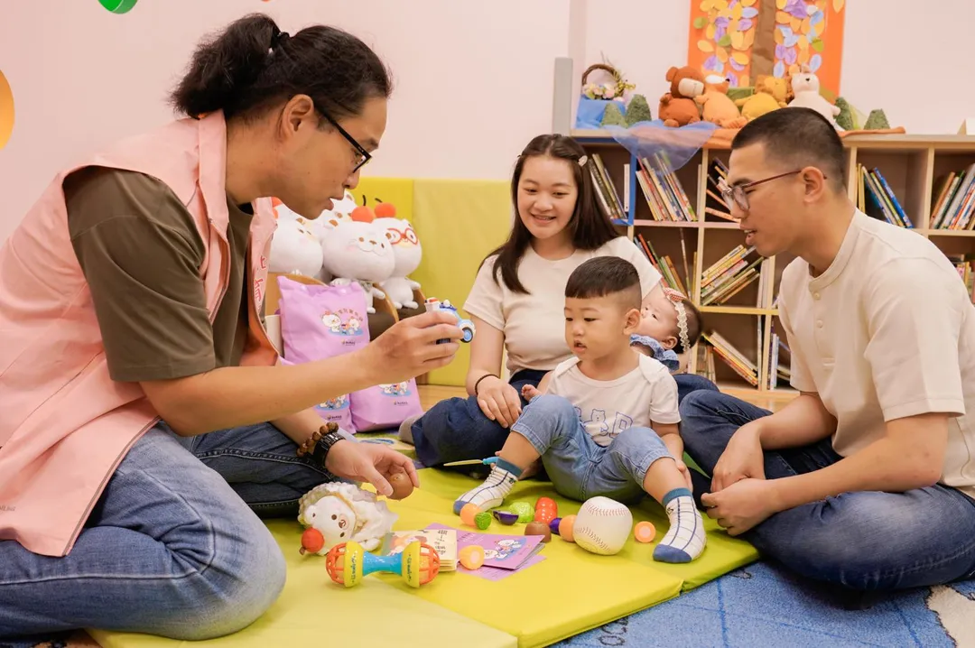 新北市設置幼兒指導員(左1),可以協助新生兒父母育兒指導,利用寶貝袋裡面的內容物來跟孩子進行發展篩檢。(圖/新北市政府提供)