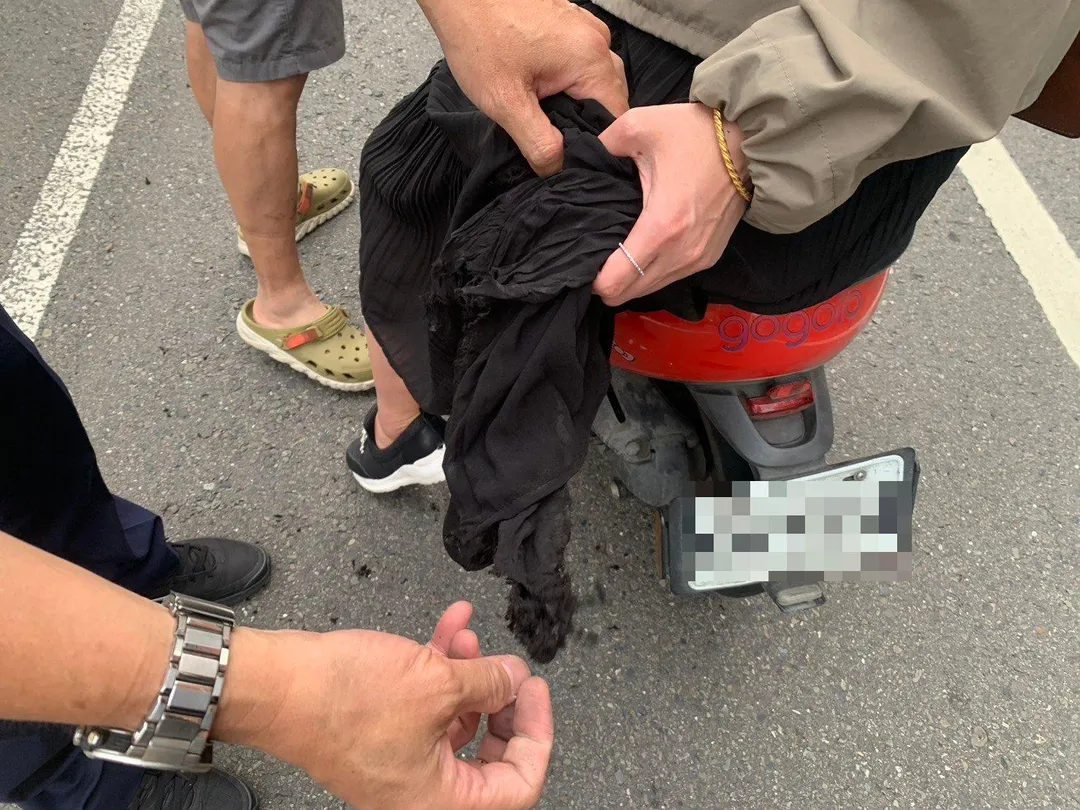 員警細心將卡入後輪內的裙擺布料一點一點慢慢抽離，歷經一番努力後，終於成功排除狀況。（圖／警方提供）
