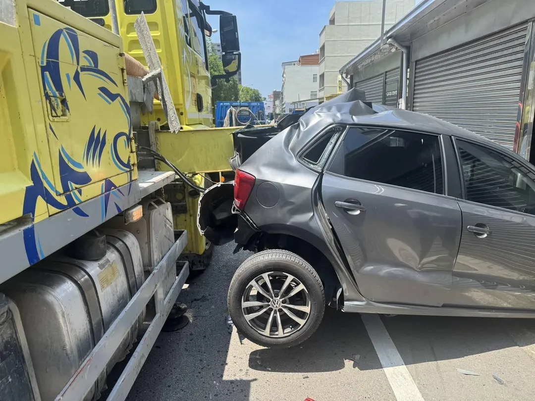 油壓支撐架滑脫撞上路邊停放小車，小車整輛被剷起。（圖／中天新聞）