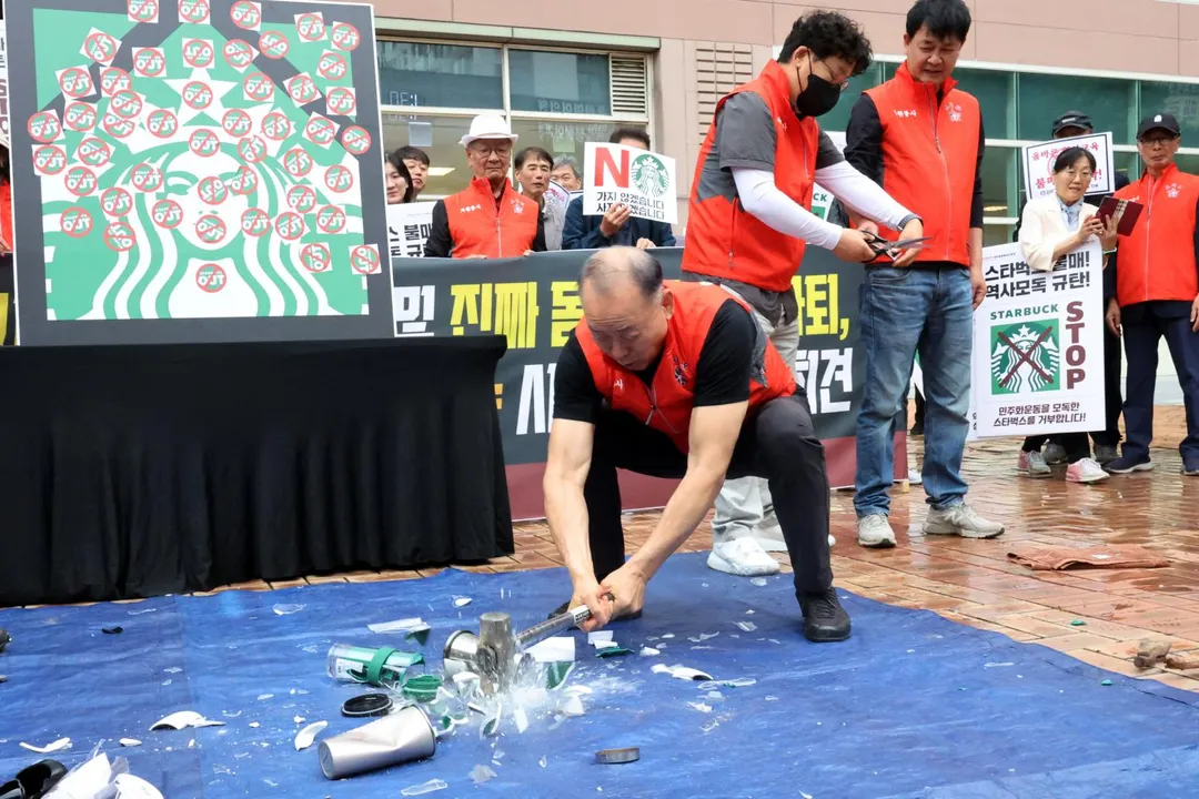 一名抗議人士怒砸星巴克保溫杯。（圖／路透社）