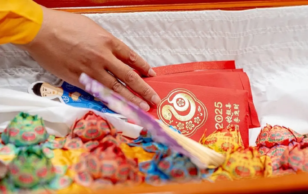 入殮蓋棺前，親友將紙蓮花與祈福物品輕輕放入棺木中，每一個動作都承載著對逝者無盡的思念與最後的道別。（圖／仁泰心蓮生命提供）