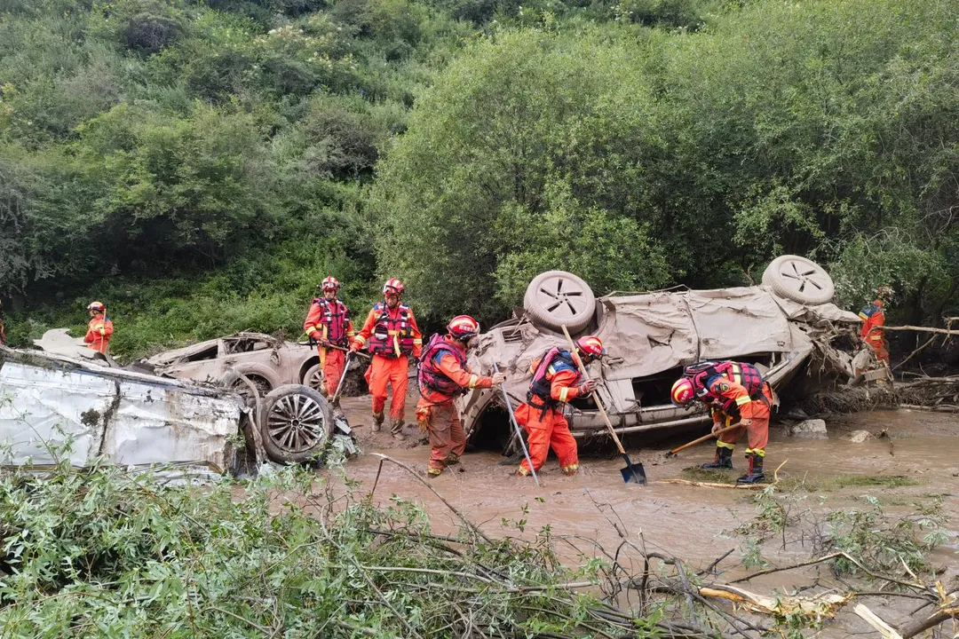 多輛轎車遭洪水沖刷而下，搜救人員逐一檢查。（圖／新華社）