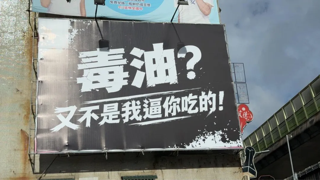 台北街頭高掛的「毒油?又不是我逼你吃的!」看板。(圖/李明賢提供)