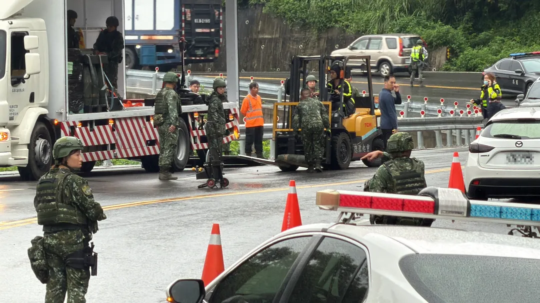 官兵搬運民間貨車滾落道路的8吋榴砲彈。(圖/中天新聞)