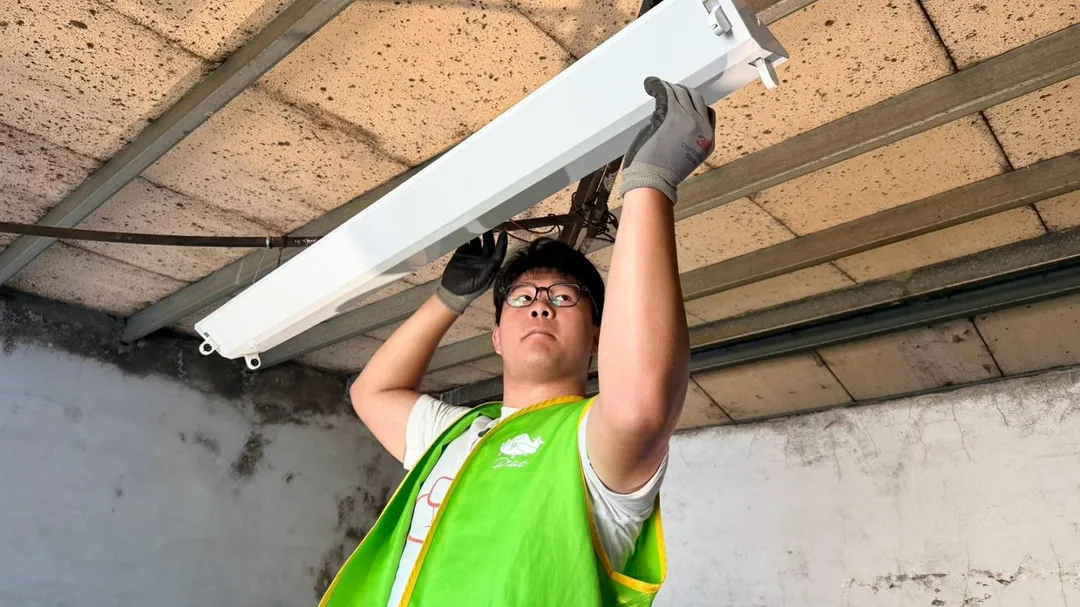 少年運用在培力園所學習的水電技能，為北海岸弱勢獨居長輩住家重新安裝日光燈。（圖／新北市社會局提供）