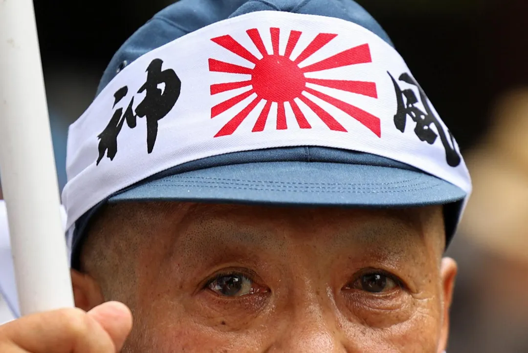 一名日本右翼成員頭戴印有旭日旗和「神風特攻隊」字樣的頭巾，15日前往靖國神社參拜。（圖／路透社）
