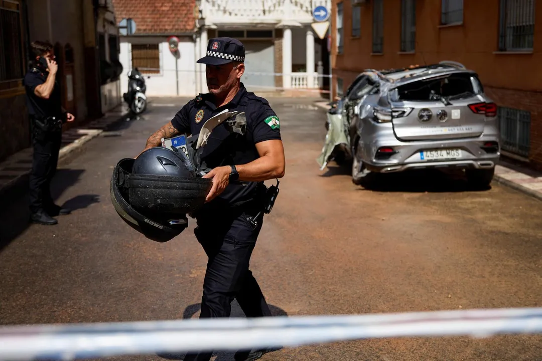 西班牙城市格拉納達（Granada）15日發生規模5地震，當地1名警察協助民眾清理毀損汽車。（圖／路透）