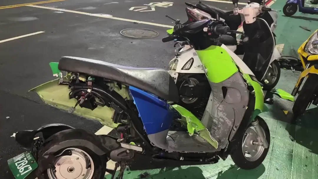 綠色Gogoro機車車殼破裂且零件外露，強烈撞擊力道甚至導致電動機車電池現場彈飛。（圖／中天新聞）