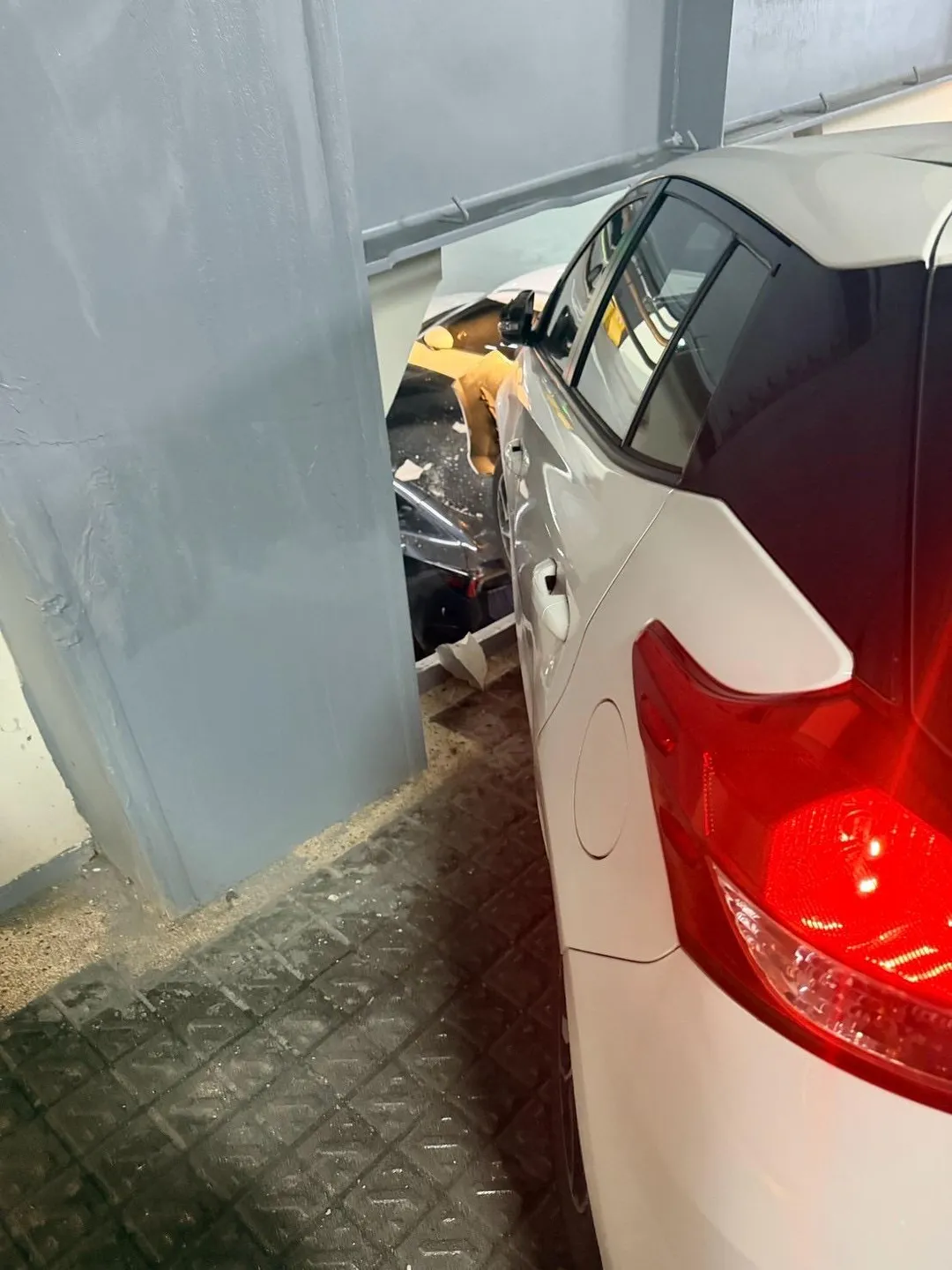 停車場牆壁破損掉落碎片，導致現場數輛車慘遭波及受損。（圖／警方提供）