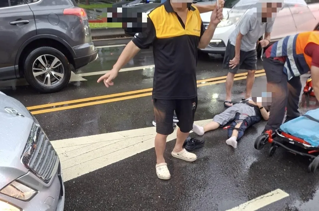 婦人被撞倒地受傷熱心民眾幫忙撐傘。（圖／翻攝畫面）