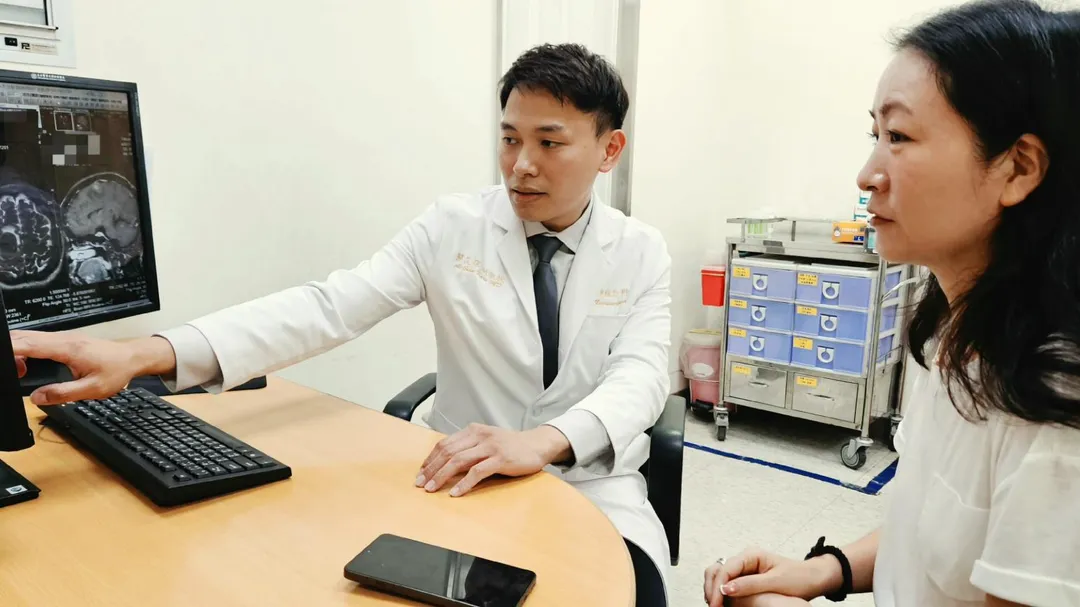 臺北醫學大學附設醫院神經外科關艾琛醫師（左）向陳小姐（右）說明腦瘤位置及壓迫情形，並了解她術後恢復狀況。（圖／北醫附醫提供）