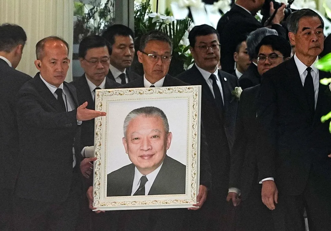 已故香港首任特首董建華20日出殯，其子手持父親遺像。（圖／路透社）