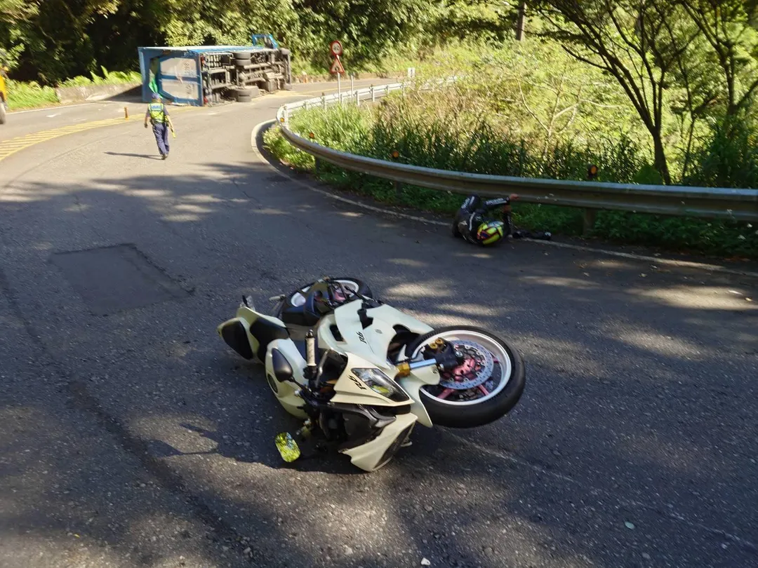 新北坪林區北宜公路20日凌晨發生大貨車翻覆事件，沒想到現場員警執行交管期間，也遭機車騎士擦撞受傷。（圖／翻攝畫面）