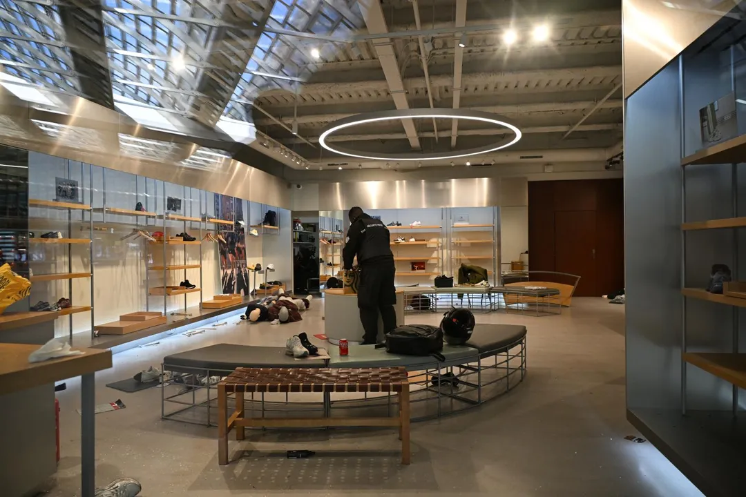 這次騷亂導致不少店家商品不翼而飛，損失慘重。圖為1名保全人員站在遭遇搶劫的店家內。（圖／美聯社）