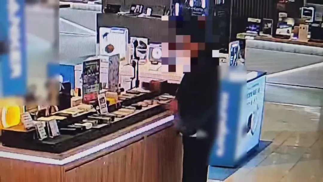 男子拿出手機跟架上擺放的行動店員「磁吸」在一起。（圖／警方提供）