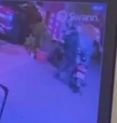 林男站在摩托車座椅上，拿噴漆噴銀樓裝設的監視器鏡頭。（圖／警方提供）