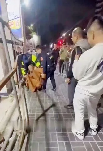 該名頭上沒有戒疤的比丘,被大群年輕男子攔下,最後遭警方過肩摔壓制上銬。(圖/中天新聞)