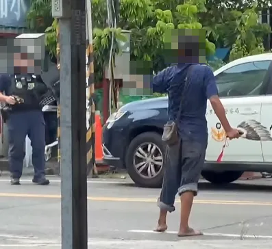 台南永康街頭29日出現1名疑似吸食強力膠精神恍惚的男子（右），他左手持大菜刀、右手揮羽扇和員警對峙。（圖／翻攝自Facebook@爆料公社公開版）