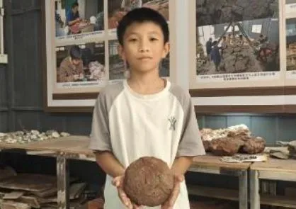 12歲學生陳梓熙在家附近花壇玩耍時發現恐龍蛋。(圖/翻攝廣州日報)