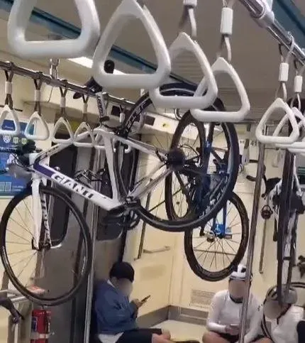 近日網路流傳一段影片，有多名自行車騎士搭乘台北捷運時，將自行車懸空掛在乘客的握把吊桿上。（圖/翻攝畫面）