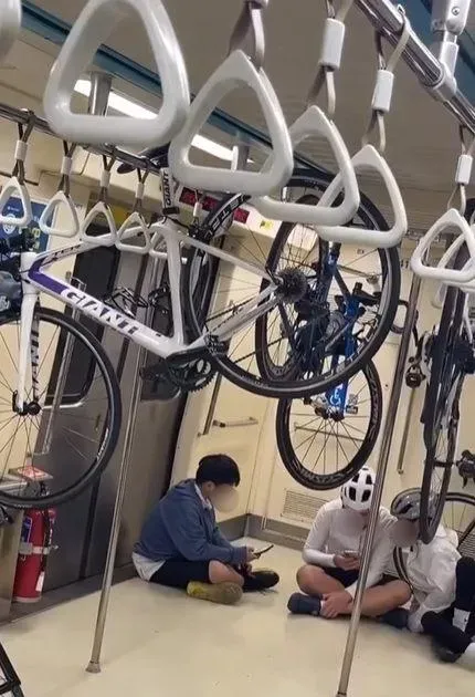 多名自行車騎士有的坐在座椅上，有的坐在地板上，但其中數人卻將自行車椅墊懸空掛在乘客的握把吊桿上，搖搖晃晃的看起來不太安全。（圖/翻攝畫面）