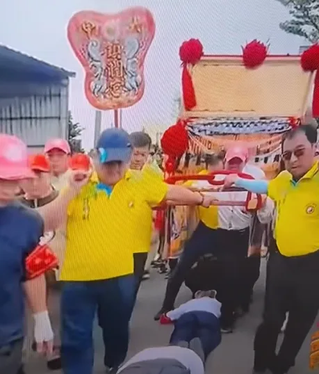 一名身穿黃衣的扶轎人員張開雙腿，直接從跪地信眾身上跨越而過。（圖／翻攝自宗教爆報粉絲團，下同）
