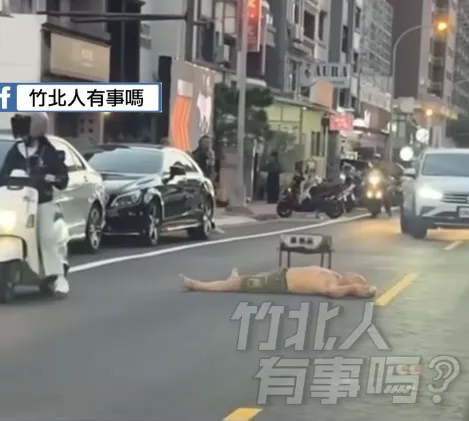 男子躺臥在竹北市成功八路馬路中央，一旁還放置了烤肉架。（圖／翻攝自「新竹爆料公社」臉書公開社團）