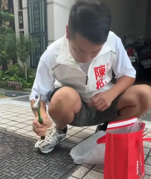 高雄市鳳山區和德里里長參選人陳柏鴻因接獲在地里民反映水溝蓋發出噪音，便自備鐵鎚與金屬墊片，親自將墊片敲入溝蓋縫隙中以減少震動異音。（圖／sw5859）