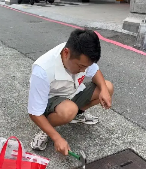 高雄市鳳山區和德里里長參選人陳柏鴻因接獲在地里民反映水溝蓋發出噪音，便自備鐵鎚與金屬墊片，親自將墊片敲入溝蓋縫隙中以減少震動異音。（圖／sw5859）