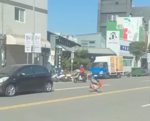 一名男子公然在車流量不小的馬路中央，以「青蛙跳」的方式蹦跳穿越。（圖／記者爆料網）