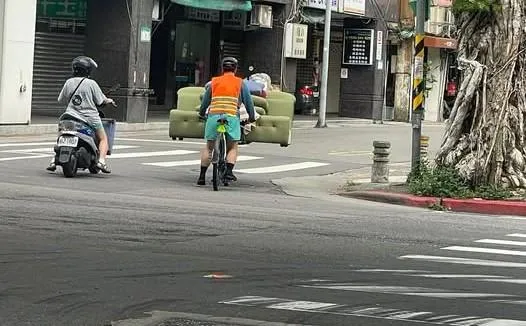 一名網友近日在北市街頭目擊，有單車騎士橫扛沙發騎車。（圖／翻攝自爆料公社臉書）