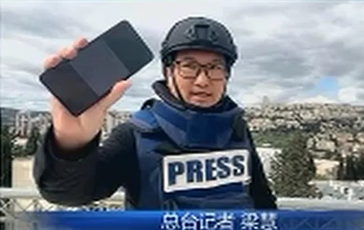 陸《央視》記者梁慧在以色列直播連線以國情況,他舉起手機示意收到緊急避難通知,隨後畫面中斷。(圖/翻攝自《央視》)