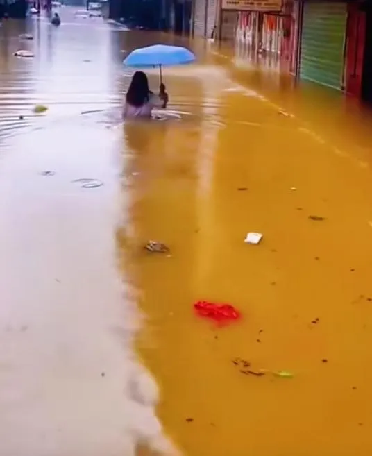 水深及腰，民眾撐傘水中行走。（圖／翻攝抖音）