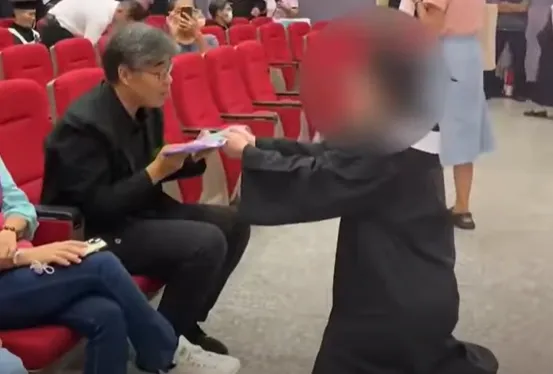 一名大眾傳播學系女學生身著學士服,在典禮現場向高雄市副市長李懷仁下跪陳情。(圖/翻攝自中時YouTube)