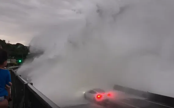 一輛特斯拉行經瑞芳陰陽海,遭白海豚颱風外圍環流掀起的巨浪吞噬。(圖/翻攝自threads)