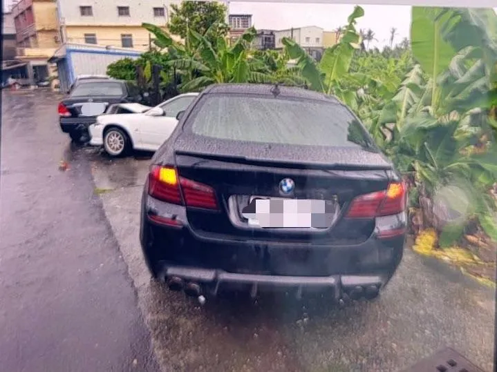 一輛BMW黑色轎車行經大寮區打鐵店街時，疑因天雨路滑失控，連撞路邊停放的4輛轎車。（圖/警方提供）