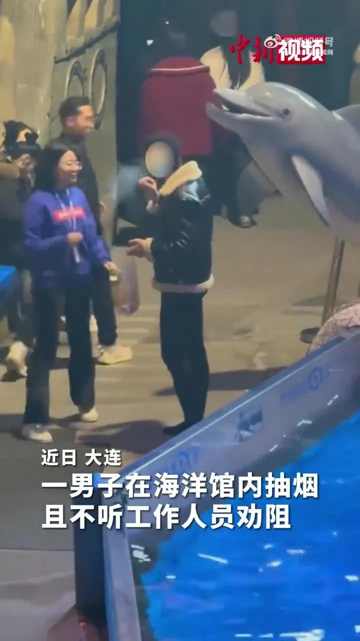 一名男子在海洋館內抽菸遭白鯨噴水。（圖／翻攝《中國新聞網》）