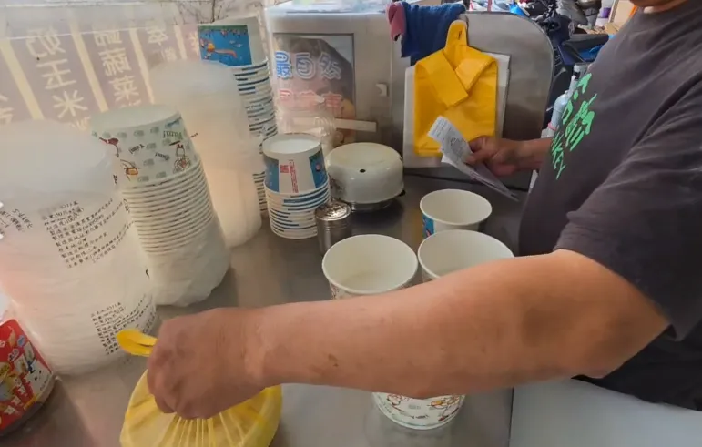 店家料理台上只放著2種紙碗和打包用的黃色塑膠袋，並未見到粉紅色的用品。（圖／中天新聞）