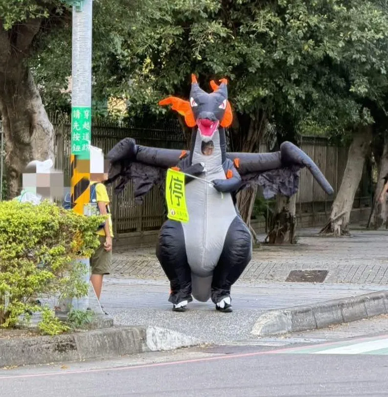 「恐龍爸爸」張晉寶穿著噴火龍裝站導護。（圖／張晉寶先生授權提供）