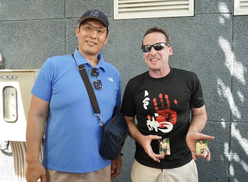 相撲力士團在看海美術館遇見台灣粉絲，外籍英語老師開心拿出小卡和相撲親方錣山矩幸（左）合照留念。（圖／屏東縣政府提供）