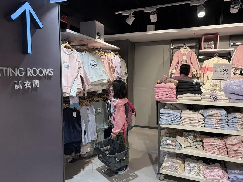 小朋友開心在衣架前挑選自己想的衣服。（圖／中央社）